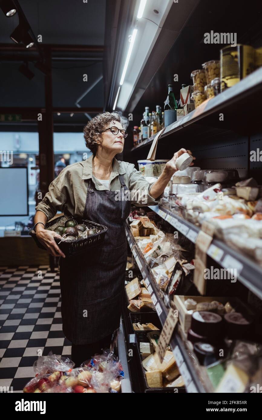 Female owner arranging product on rack at delicatessen store Stock ...