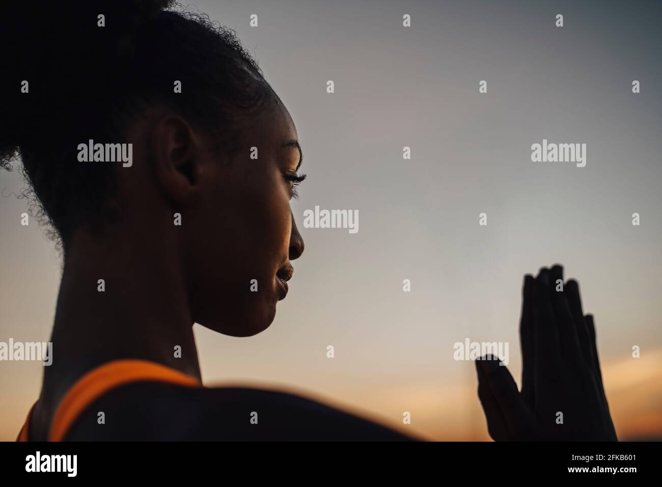 Young sportswoman practicing yoga against sky during sunset Stock Photo