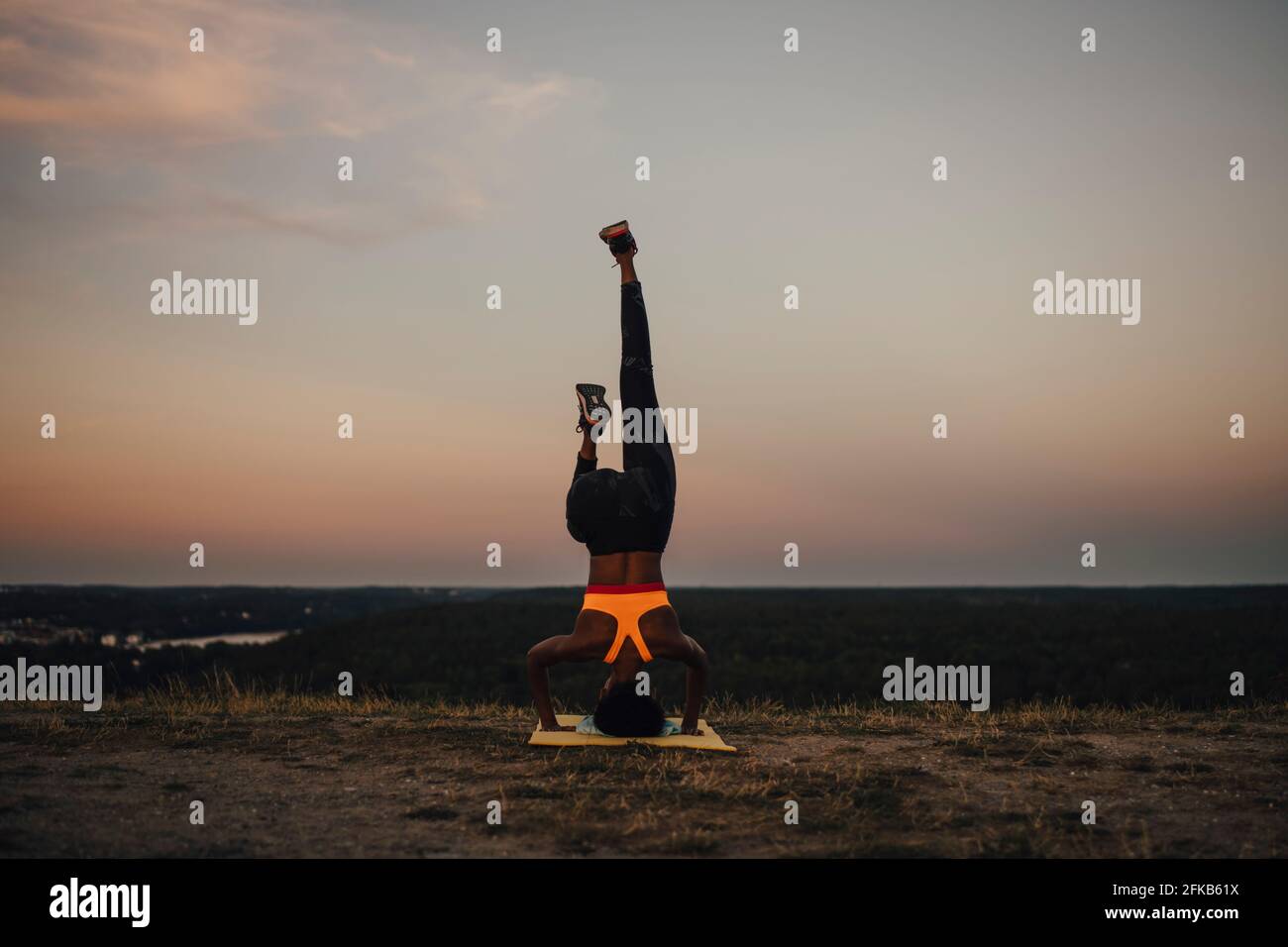 Young female athlete practicing yoga during sunset Stock Photo