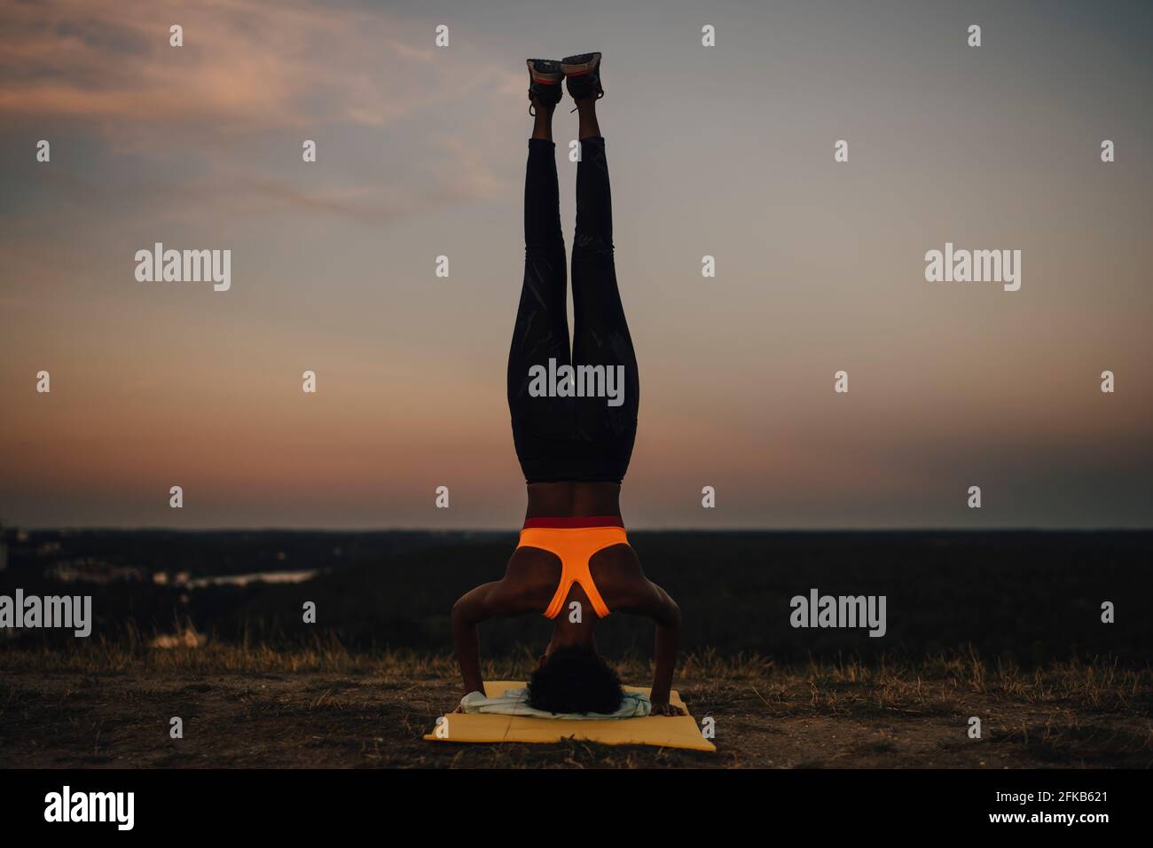 Sportswoman practicing yoga during sunset Stock Photo