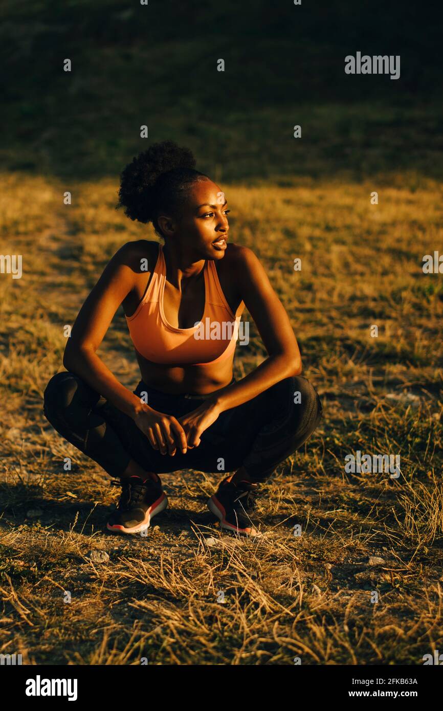 Sportswoman contemplating while crouching on land during sunset Stock Photo