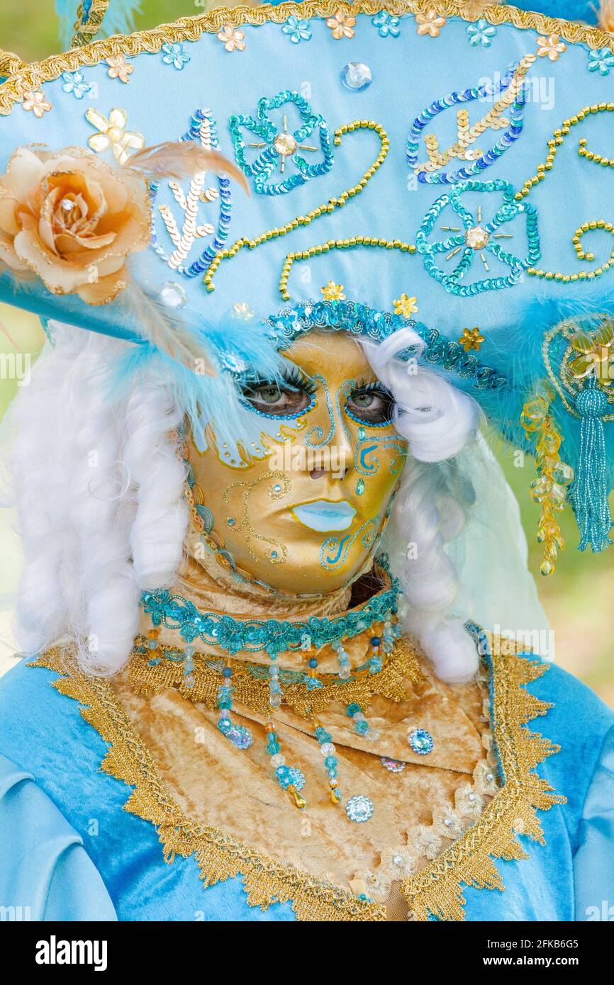 Golden venetian mask wearing a wide light blue hat Stock Photo