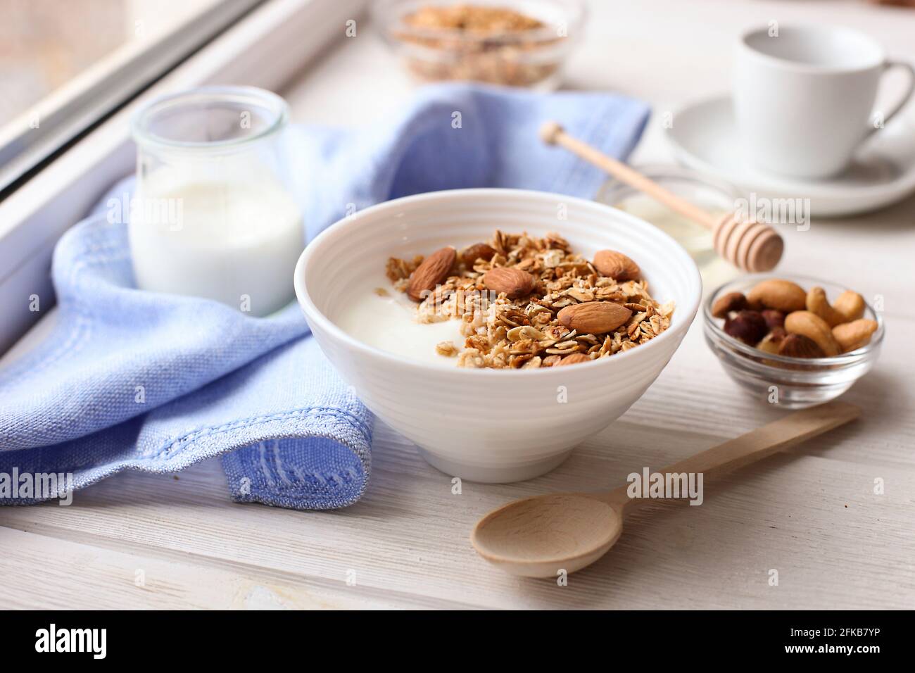Healthy breakfast. Yogurt with granola and nuts on window sill Stock Photo