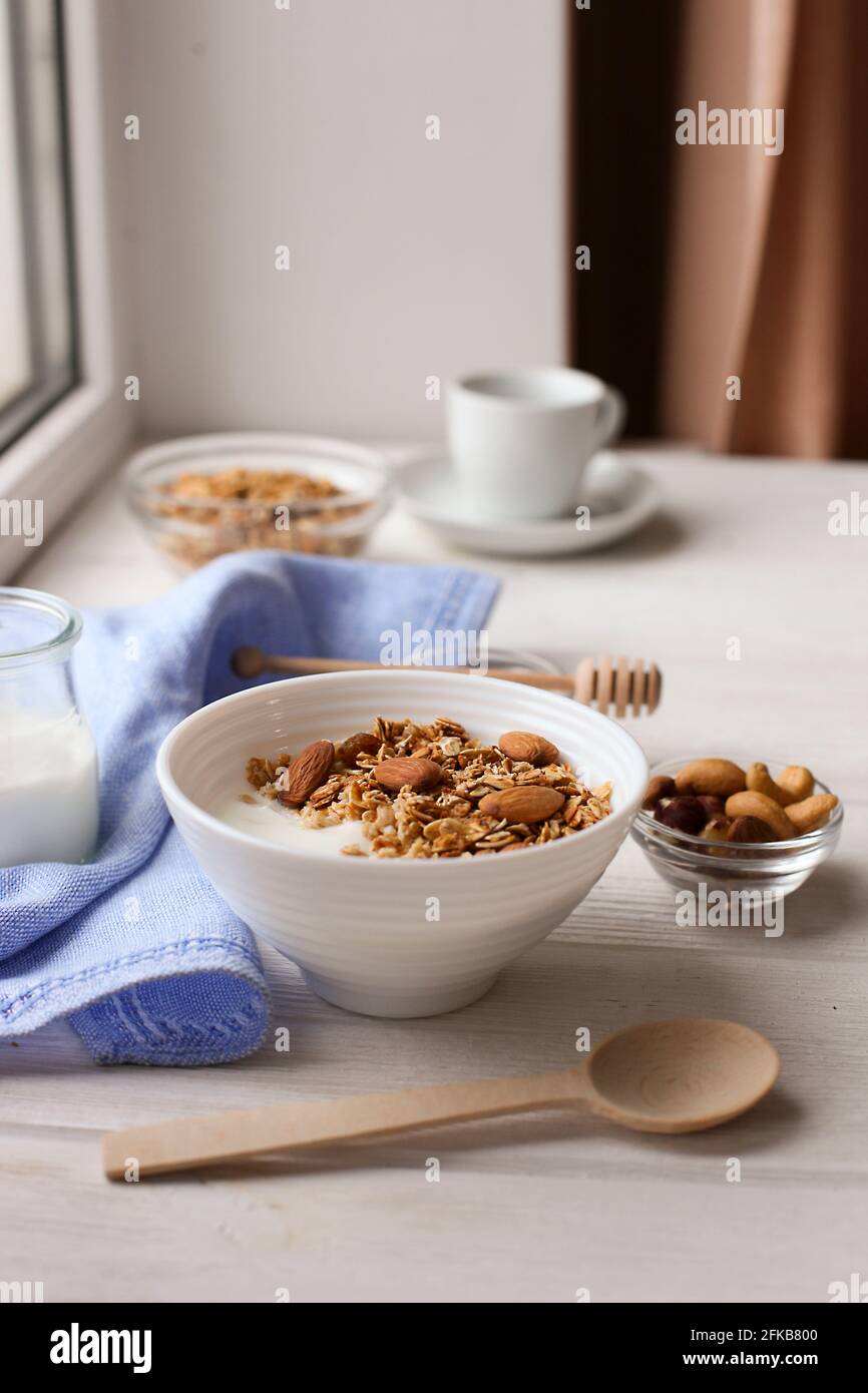 Healthy breakfast. Yogurt with granola and nuts on window sill Stock Photo