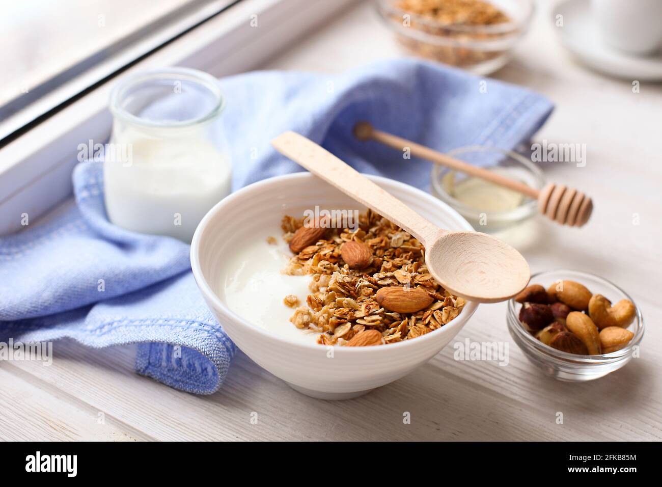 Healthy breakfast. Yogurt with granola and nuts on window sill Stock Photo
