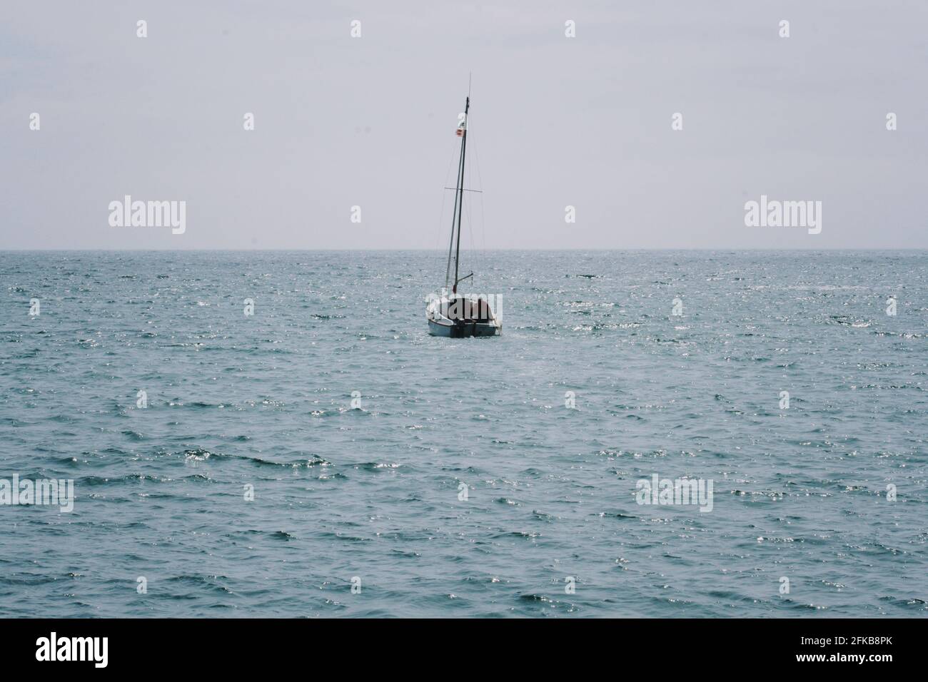 sailboat moves away into the sea Stock Photo