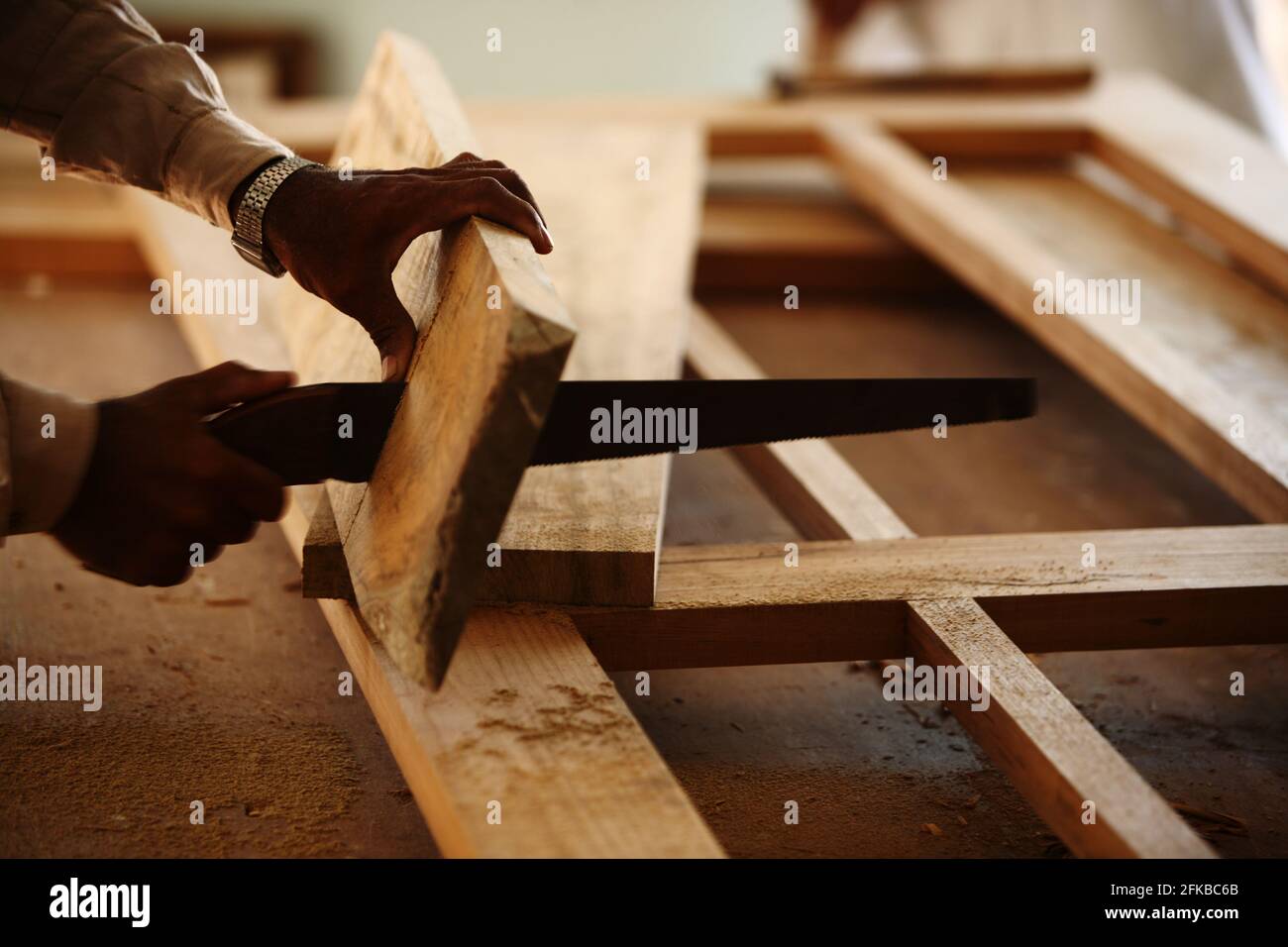 Carpenter is making a panel door frame of teak wood in a room of under