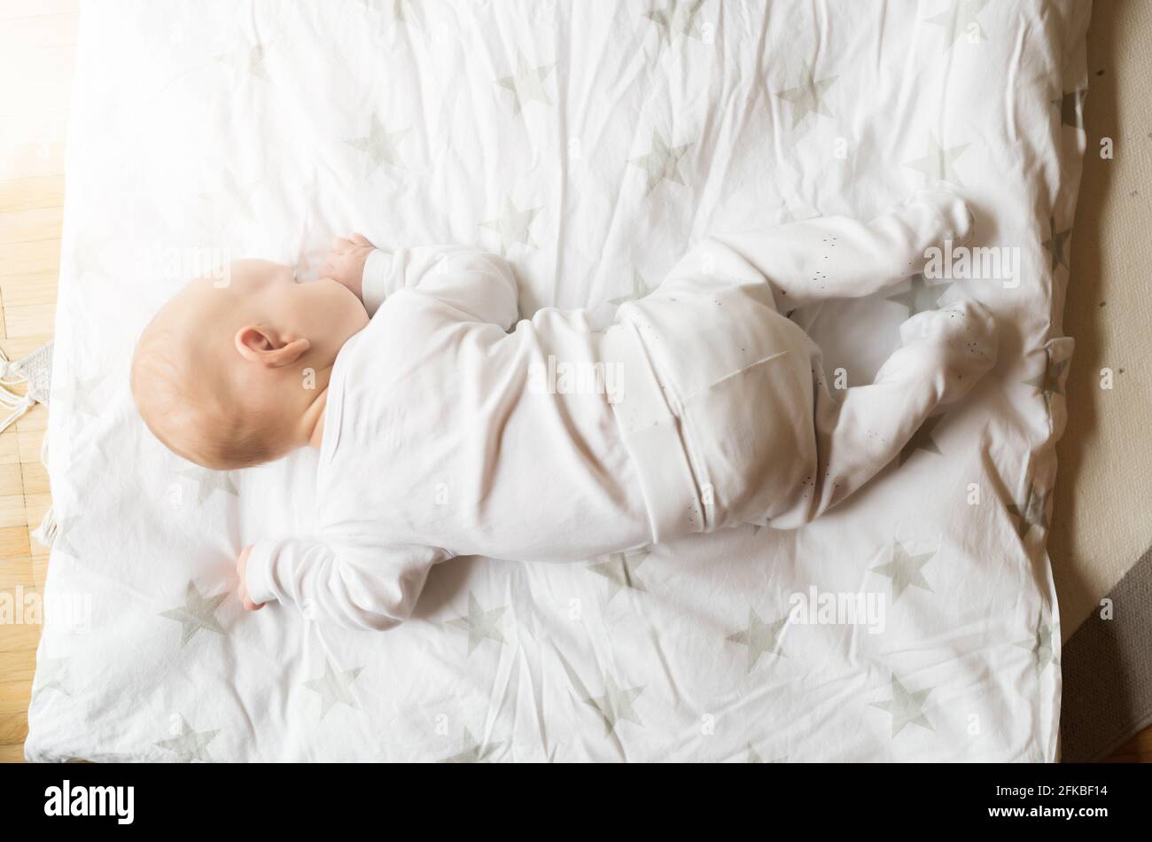directly above view of one month old baby on blanket trying to lift his head Stock Photo