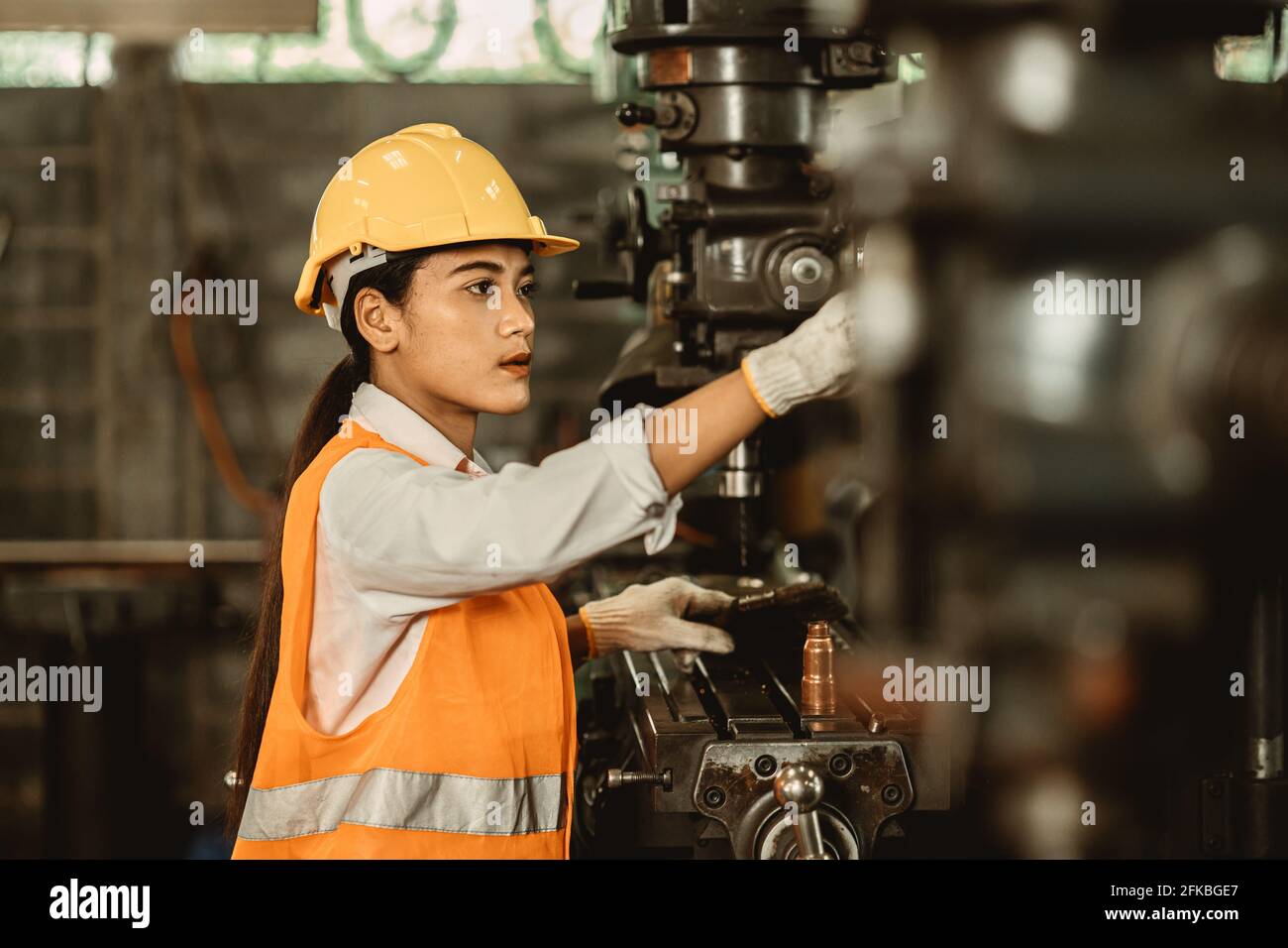 Young female women attend worker happy working in metal factory workplace work engineer fix maintenance heavy industry machine. Stock Photo