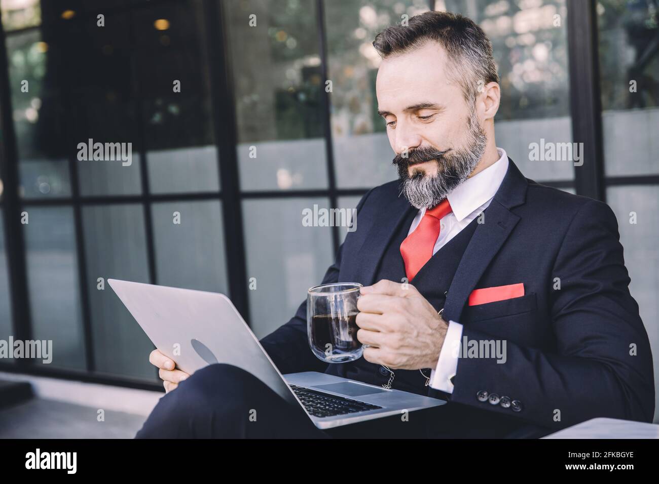 Hispanic latin businessman beard happy enjoy working with laptop computer relax at cafe drinking hot coffee Stock Photo