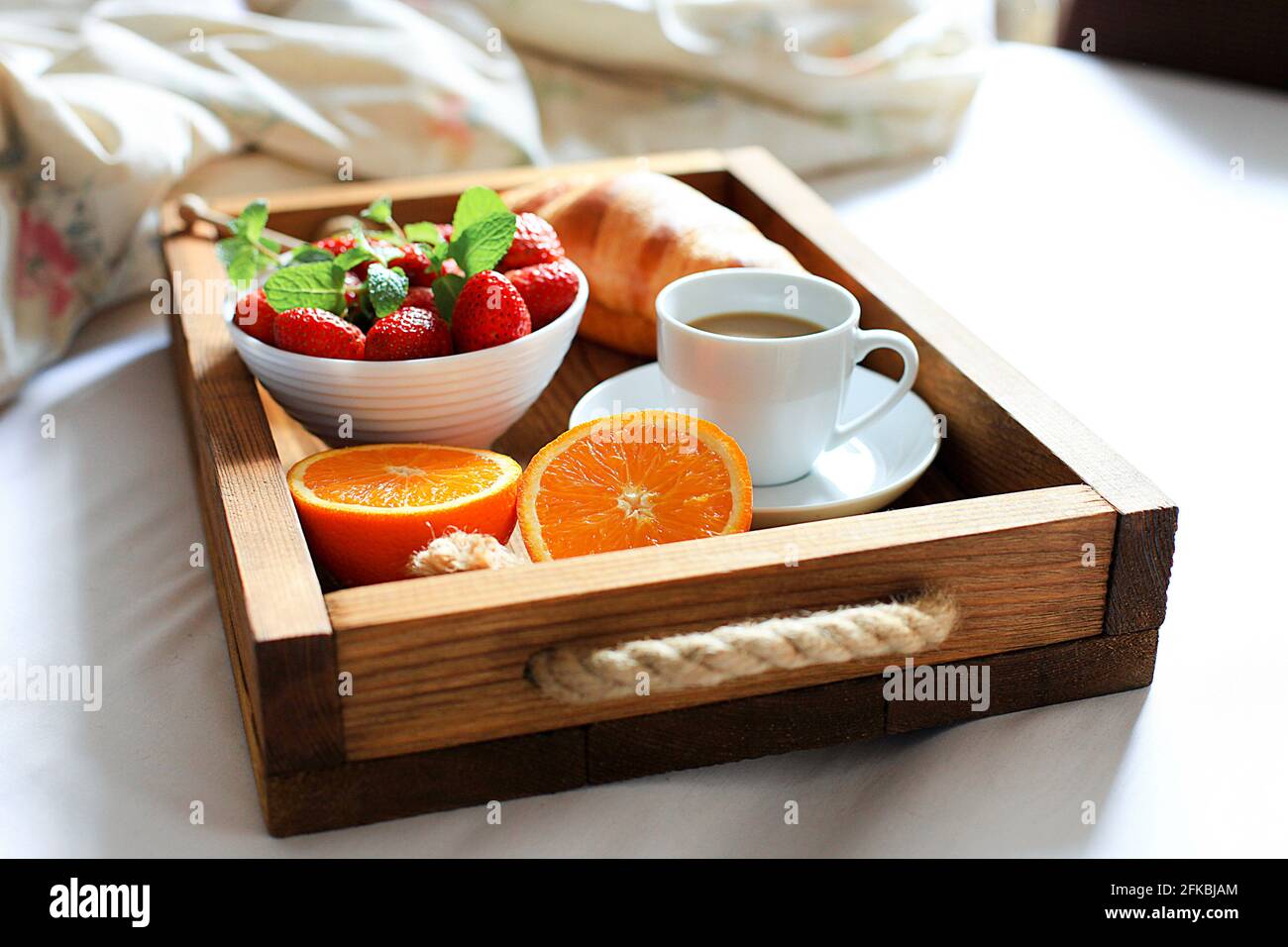Breakfast in bed tray with cup of coffee, fresh french croissant and