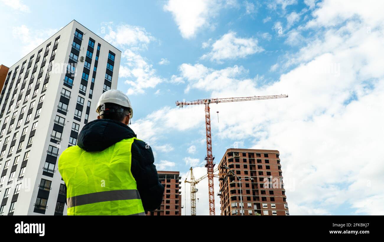 Consulting engineer at construction site holding blueprint in hand