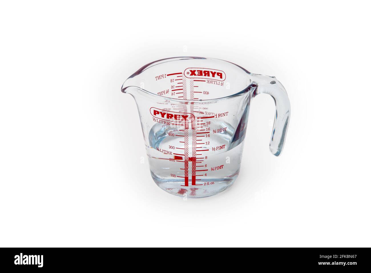 Glass measuring jug half filled with water on a white background Stock Photo