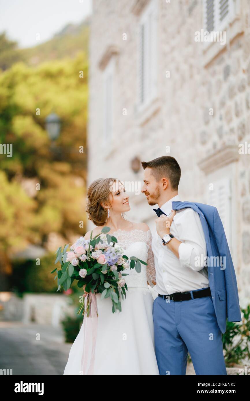 The bride and groom stand hugging near a beautiful brick house in the ...