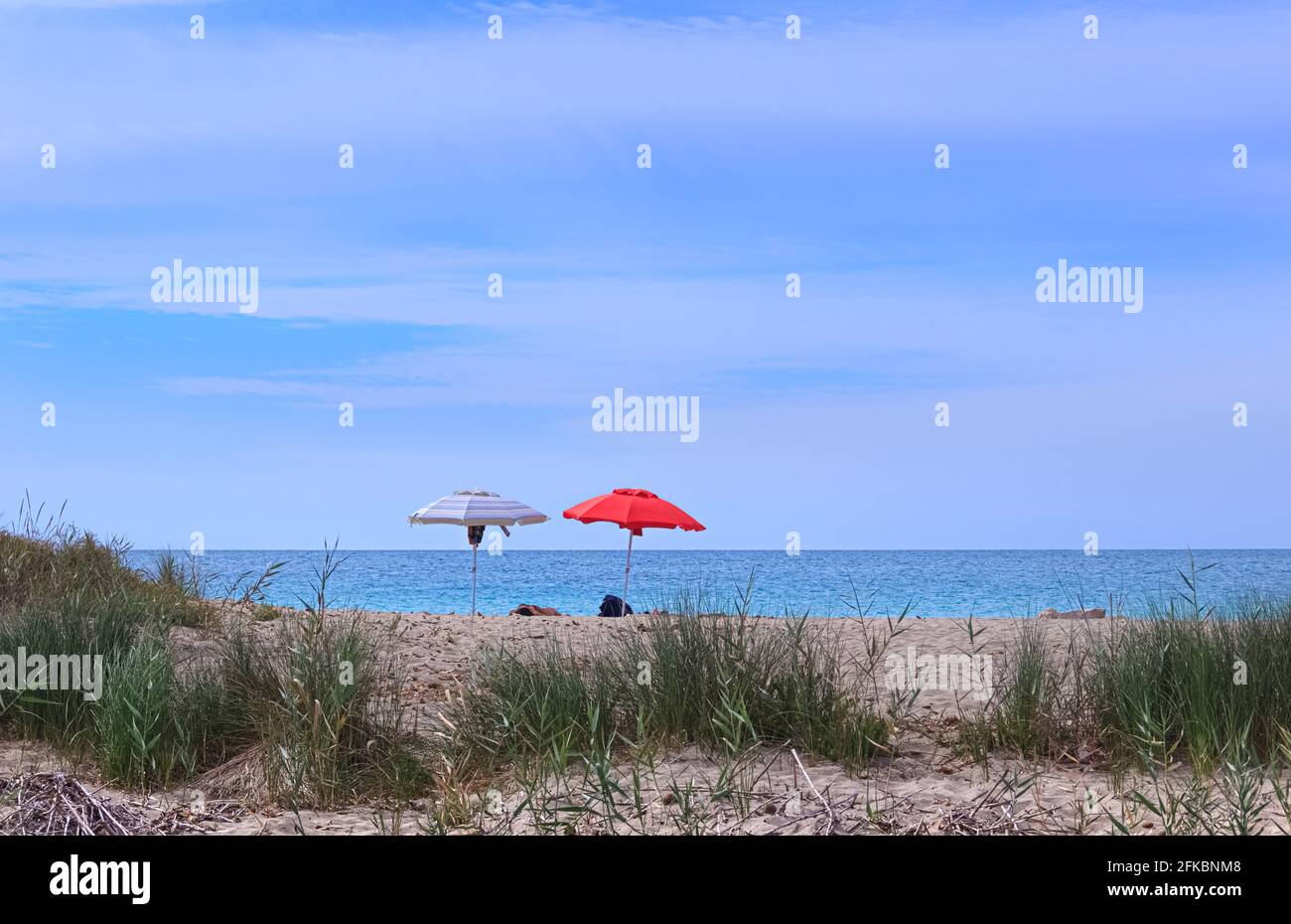 Relax on the beach, Apulia (Italy). Sunbathing tourists with lonely umbrella. Stock Photo