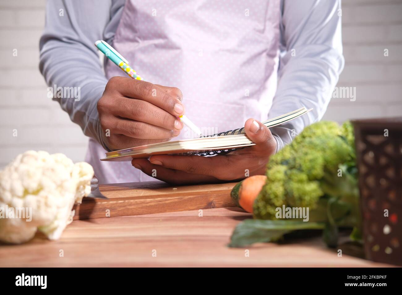 young man writing diet pan on notepad on kitchen table  Stock Photo