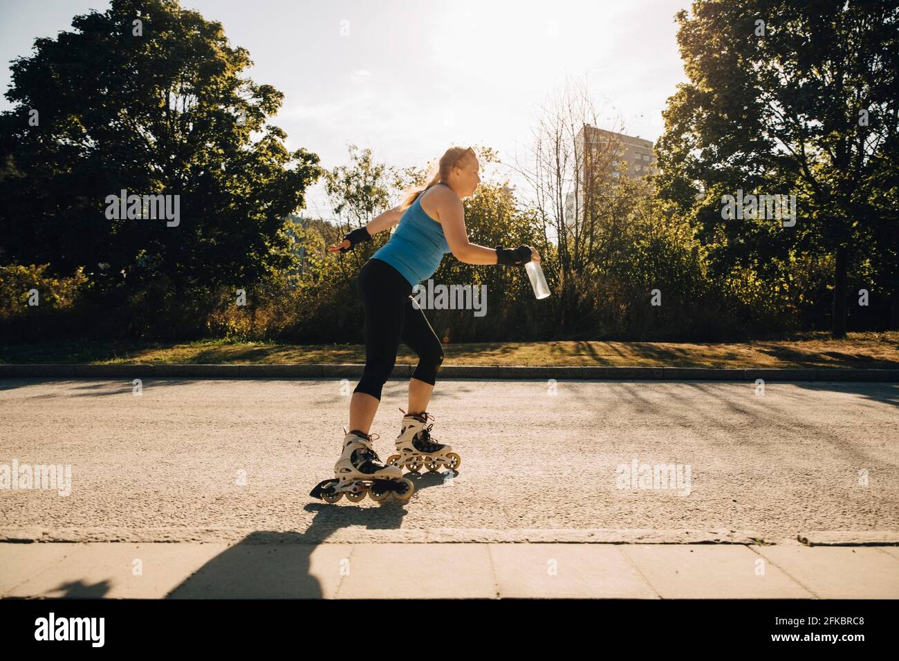 Female athlete roller skating on street during sunny day Stock Photo