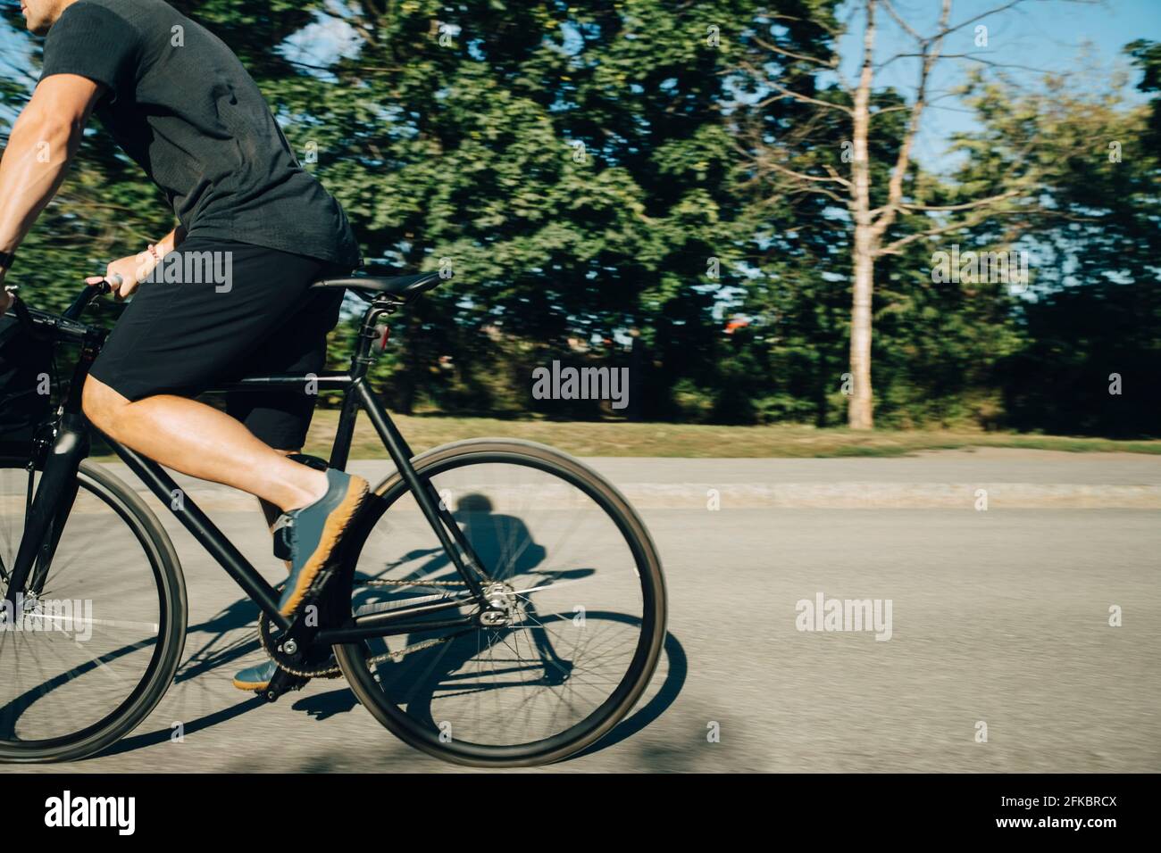 Low section of sportsman cycling on road during sunny day Stock Photo