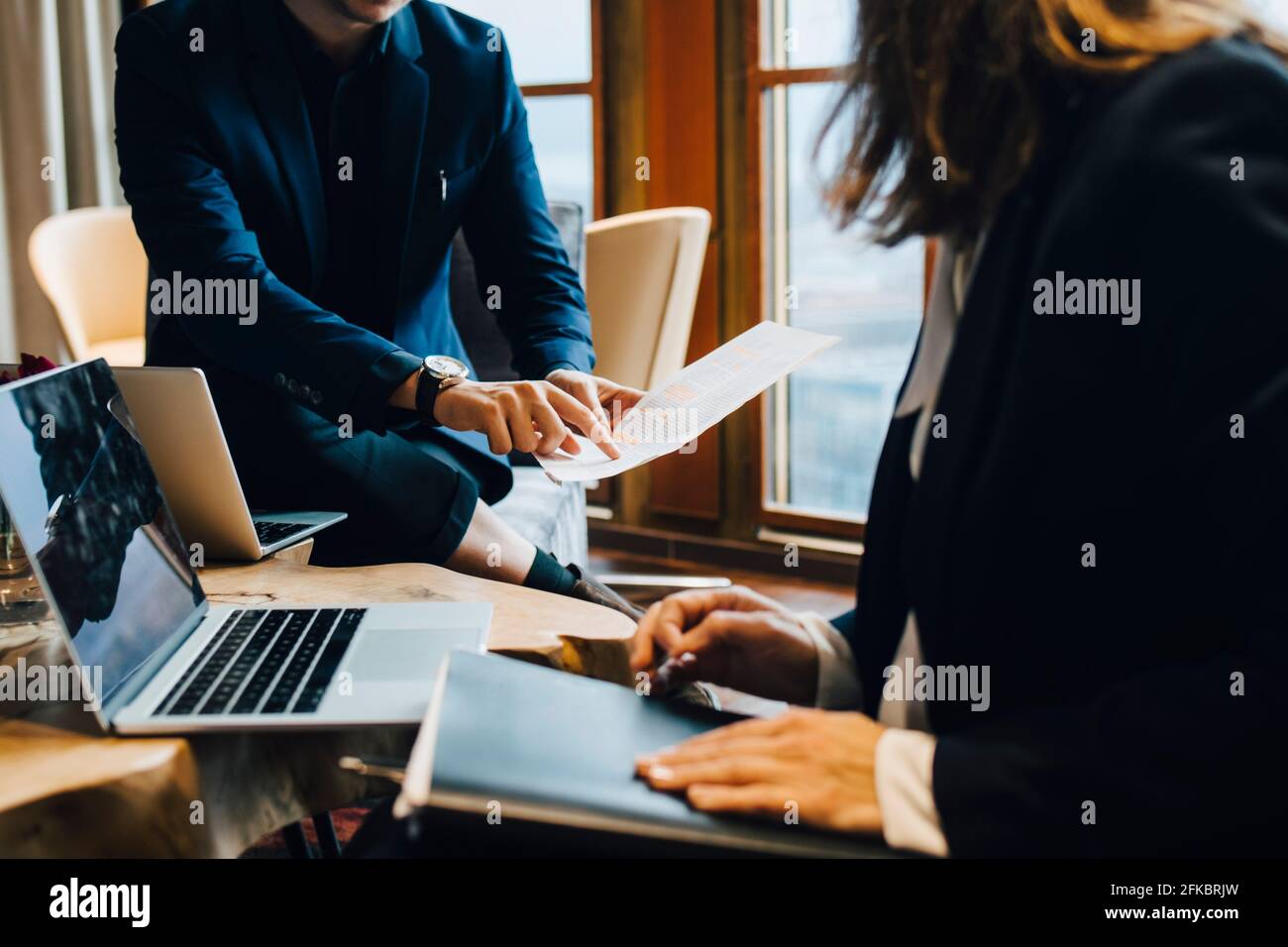 Midsection of male and female colleagues discussing over document in office Stock Photo