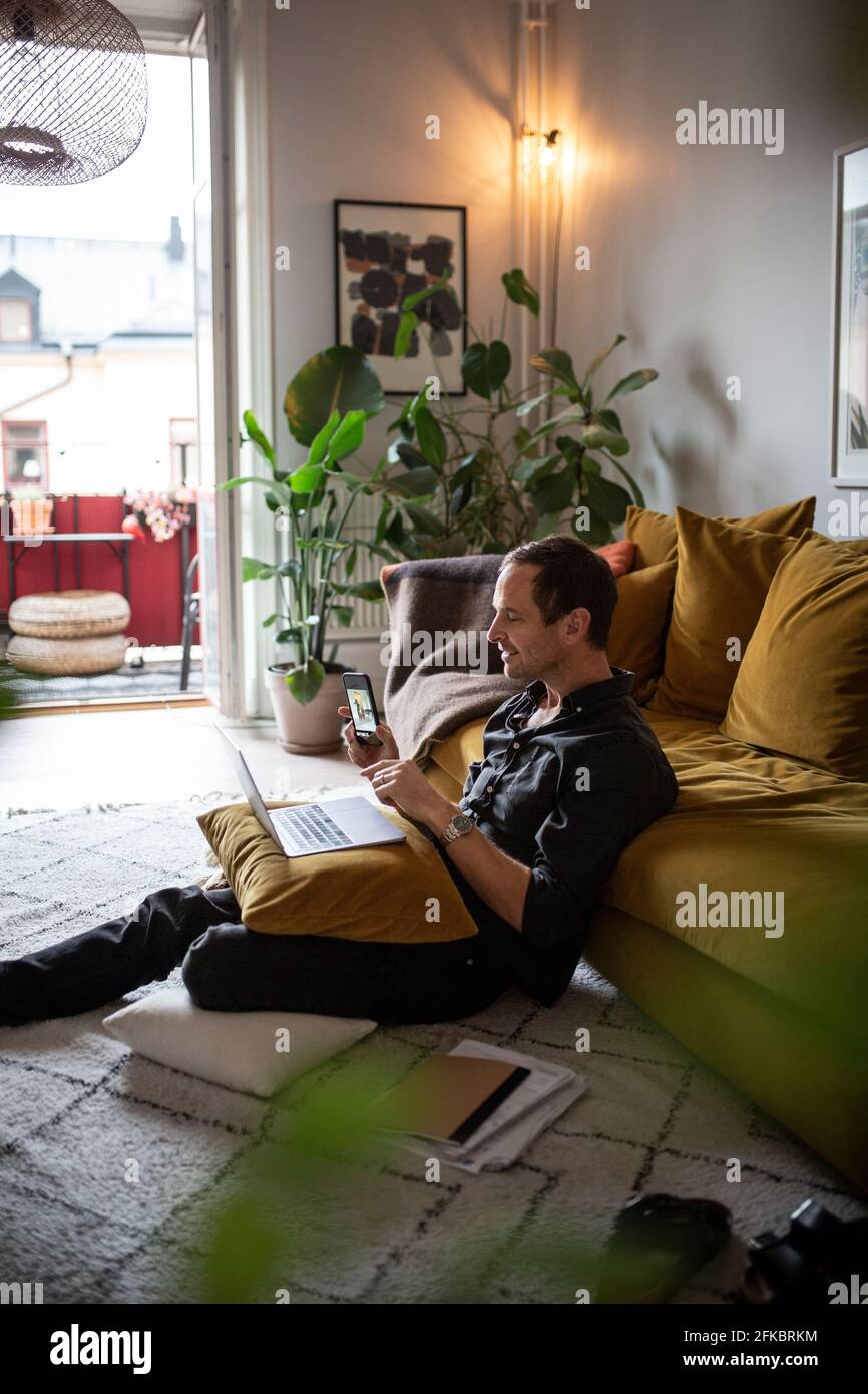 Businessman using smart phone while working at home during pandemic Stock Photo