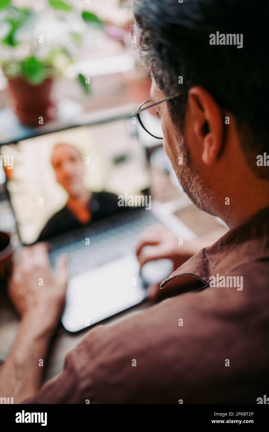 Male entrepreneur on video conference with colleague at home during pandemic Stock Photo