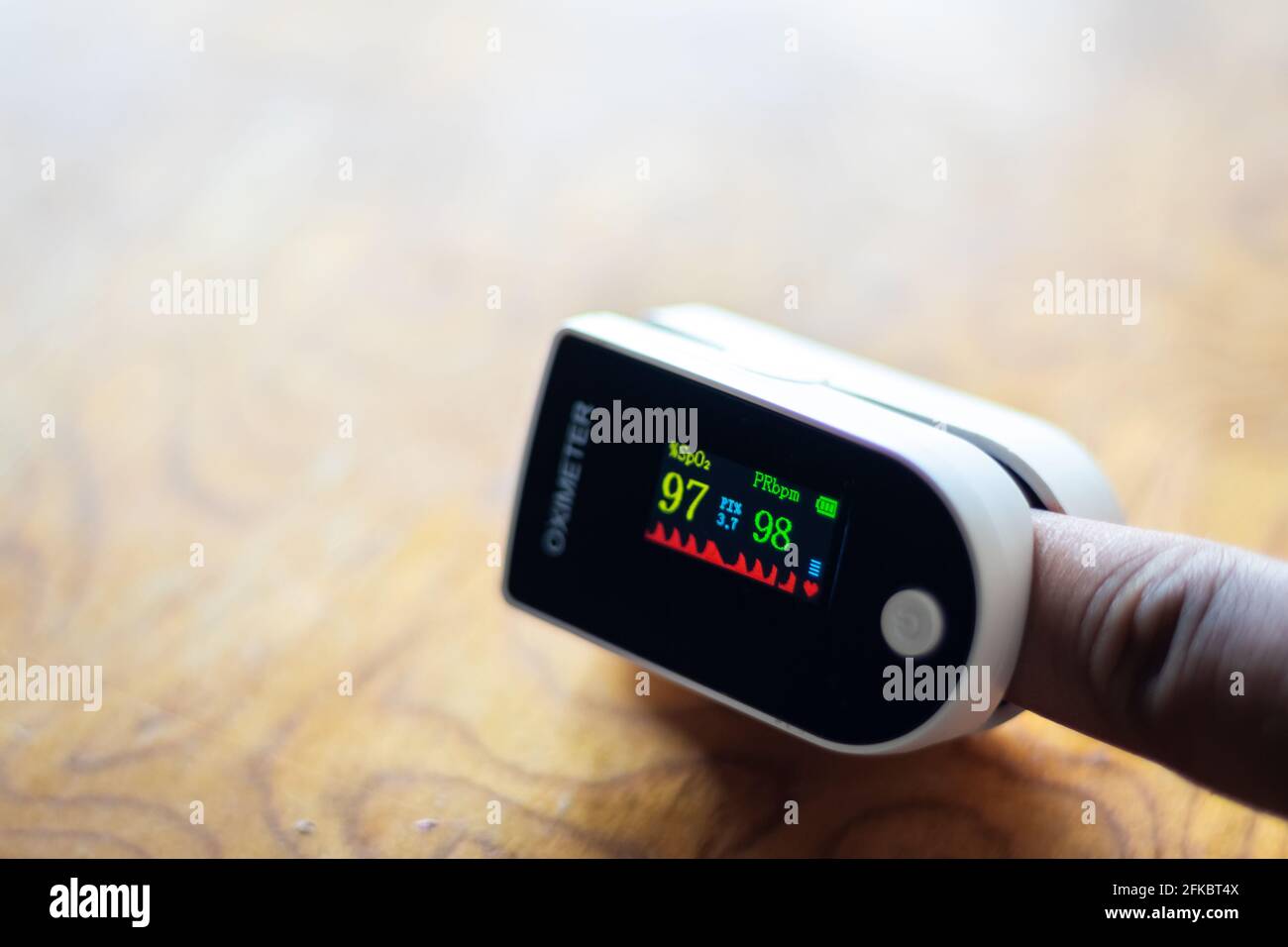 Pulse Oximeter to measure oxygen saturation level in body. Asian male hands puts index finger inside portable oximeter to measure oxygen level. Stock Photo