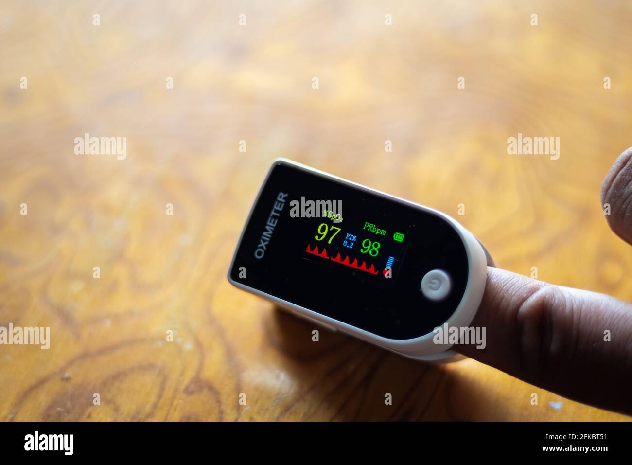 Pulse Oximeter to measure oxygen saturation level in body. Asian male