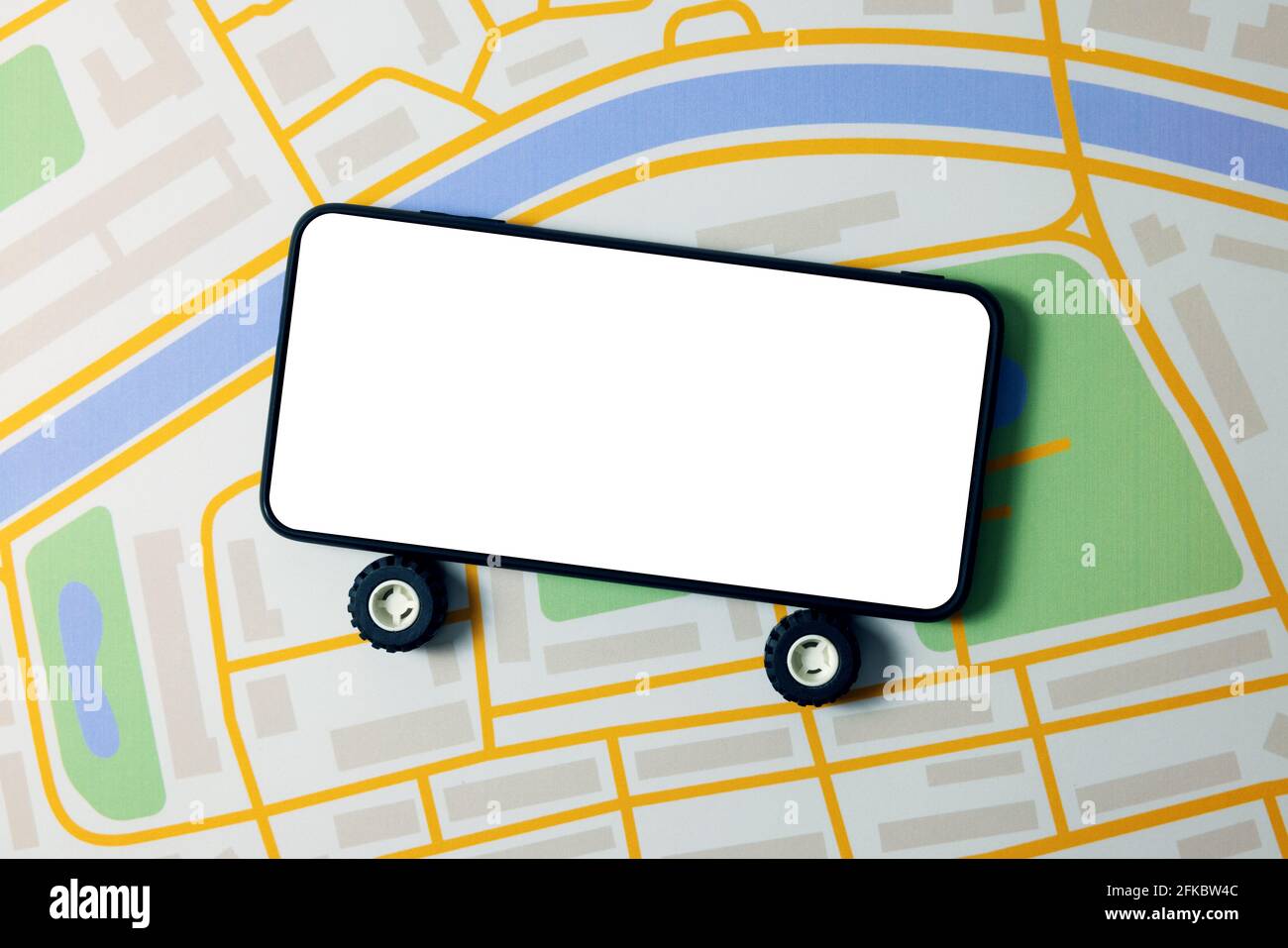 carsharing, car rental and taxi service mobile app - phone with wheels and blank screen on city map Stock Photo
