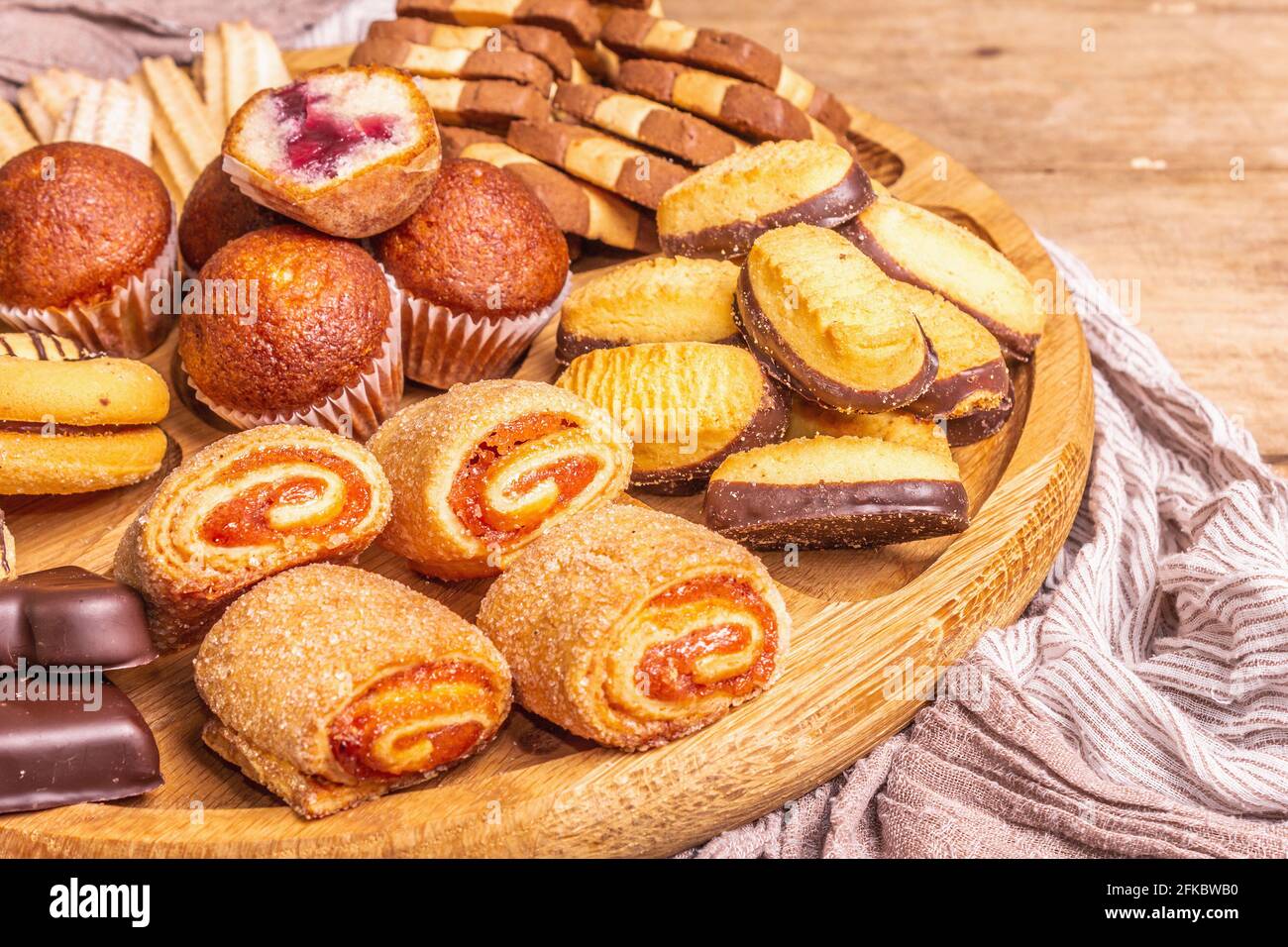 Assorted various cookies and muffins. Wooden combination plate on old boards table, close up Stock Photo