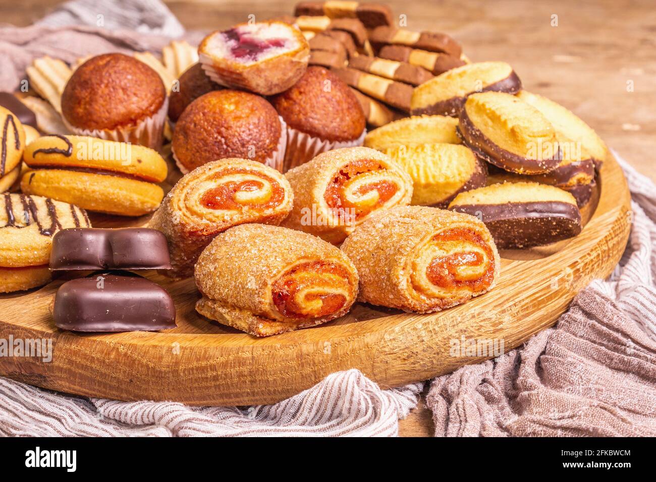 Assorted various cookies and muffins. Wooden combination plate on old boards table, close up Stock Photo