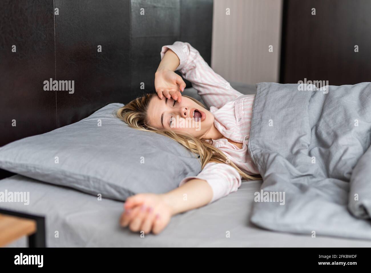 Portrait of woman lying on bed sleeping yawning wakeup in bed at home