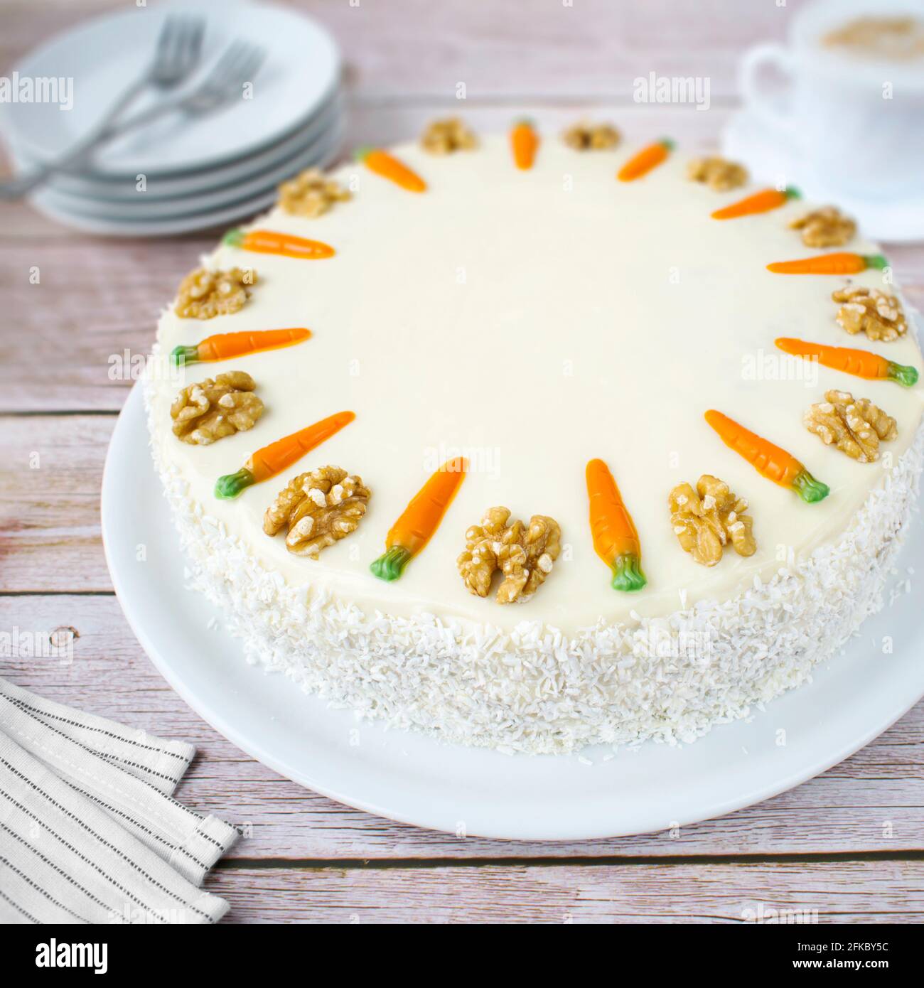 Homemade carrot cake with coconut cream. Structured cake with walnuts, pineapple and coconut flakes on a wood background. Stock Photo