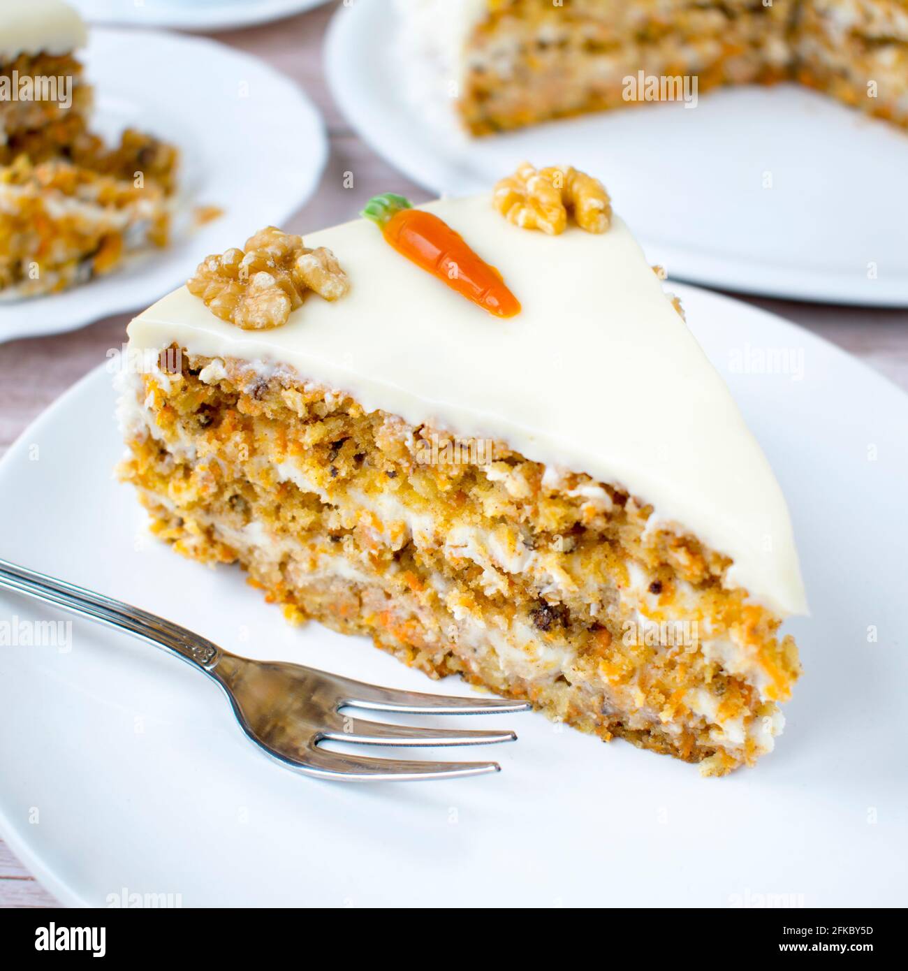 Homemade carrot cake with coconut cream. Structured cake with walnuts, pineapple and coconut flakes on a wood background. Stock Photo