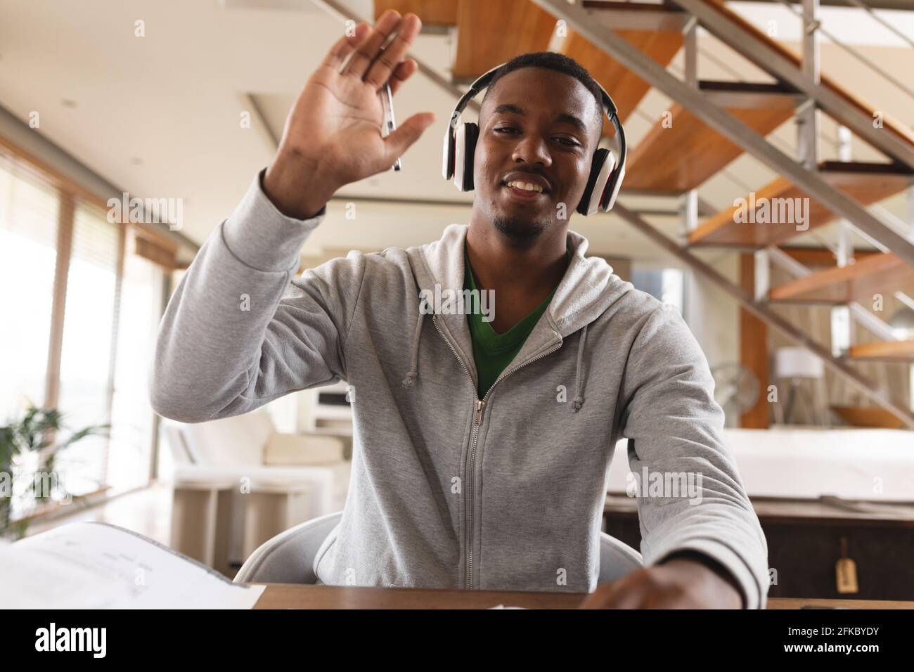 Portrait of african american young man wearing headphones waving while looking at the camera Stock Photo