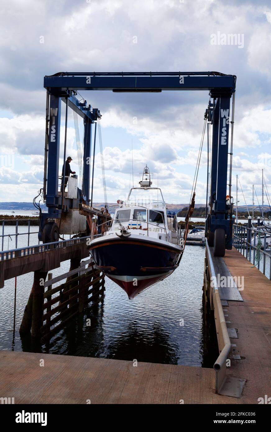 Motor boat on the boat lift being put into the water at the beginning