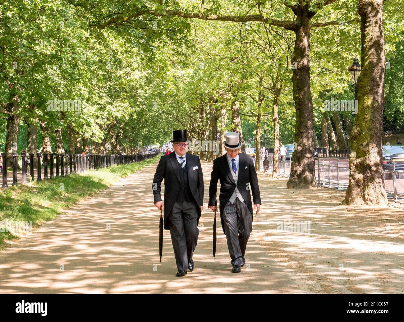 Men in morning suit and top hats strolling down Constitution Hill alongside Green Park, London, UK Stock Photo