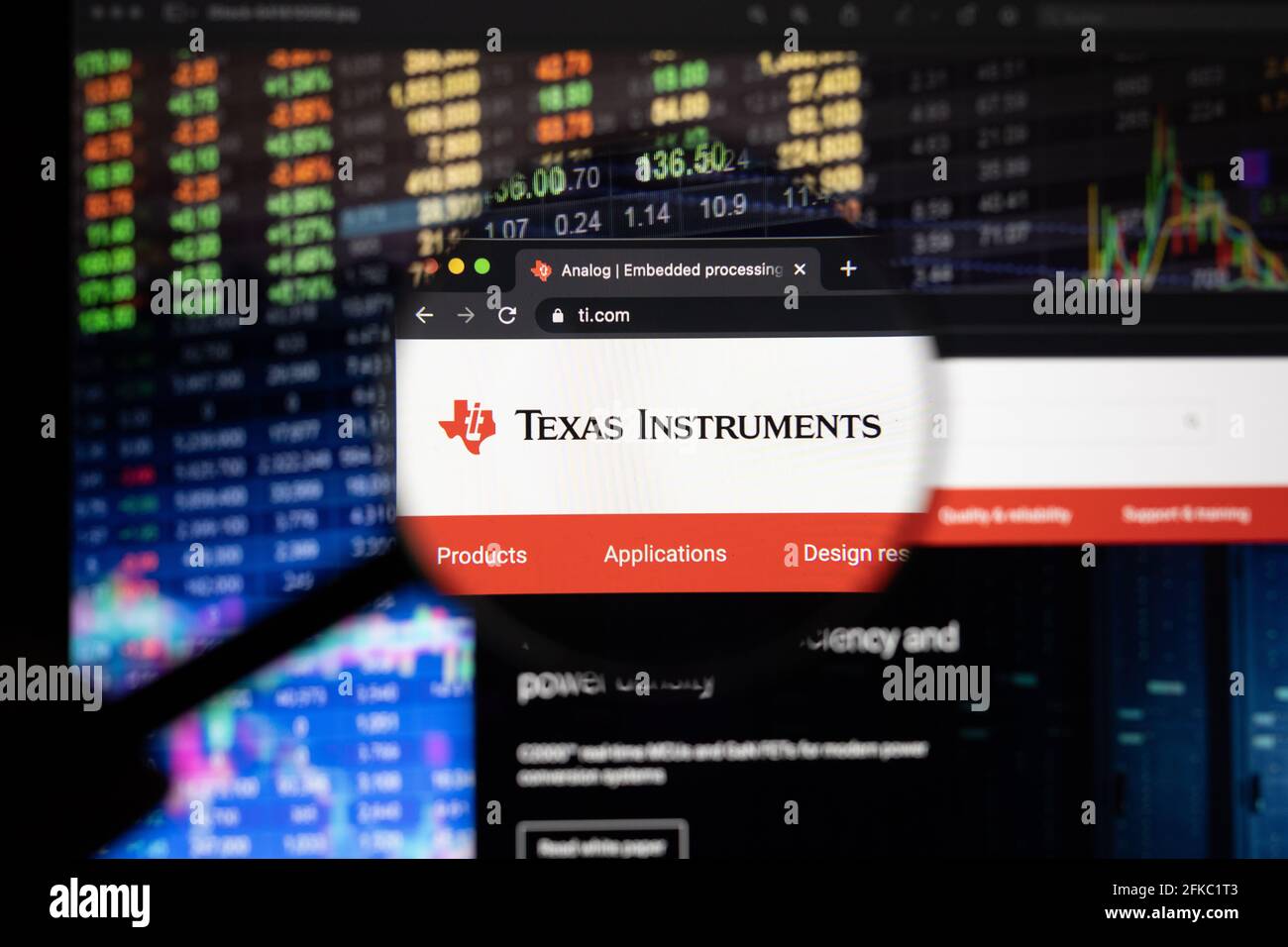 Texas Instruments company logo on a website with blurry stock market developments in the background, seen on a computer screen through a magnifying gl Stock Photo