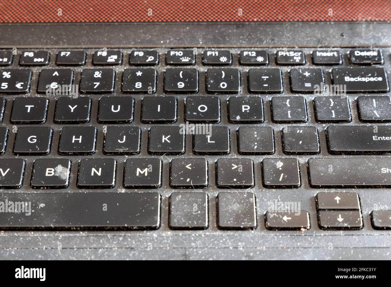 Close-up on dirty and unhygienic computer laptop keyboard, full of dust and particles Stock Photo