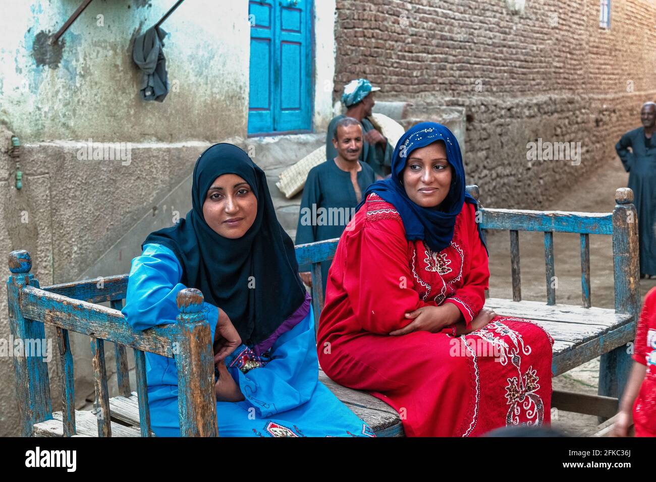 Two Egyptian women with headscarves, seated on a bench in a rural village on an island in the Nile River Stock Photo