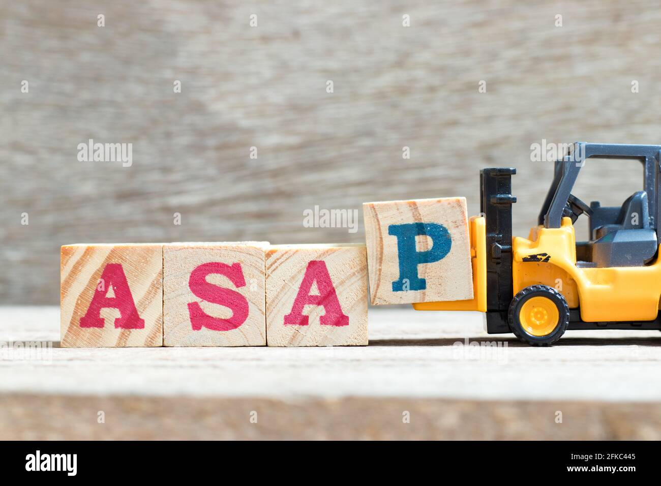 Toy forklift hold letter block p to complete word asap (abbreviation of as soon as possible) on wood background Stock Photo