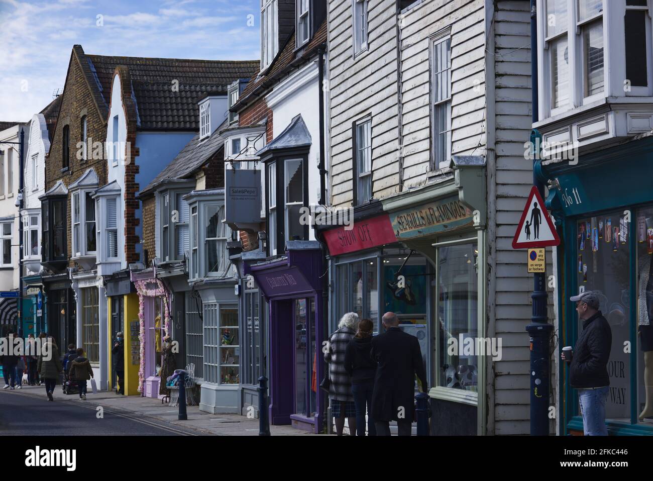 Shoppers browsing the independent shops in Harbour Street, Whitstable, UK on a bright sunny Sunday morning in April Stock Photo