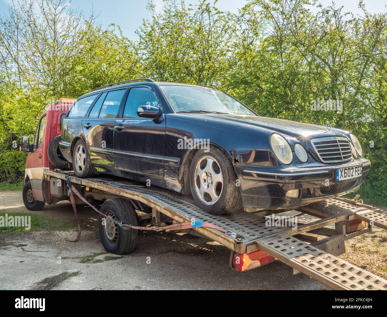 An old Mercedes estate car on a low loader / flatbed truck / recovery vehicle, ready to be taken away. Stock Photo