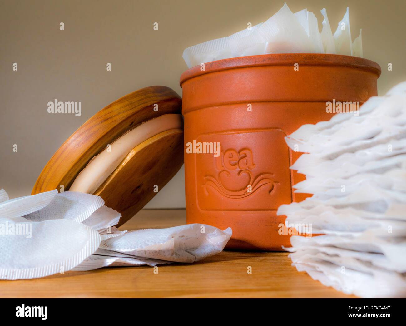 Closeup of tea bags in and around a terracotta storage container and its sealing lid. Stock Photo