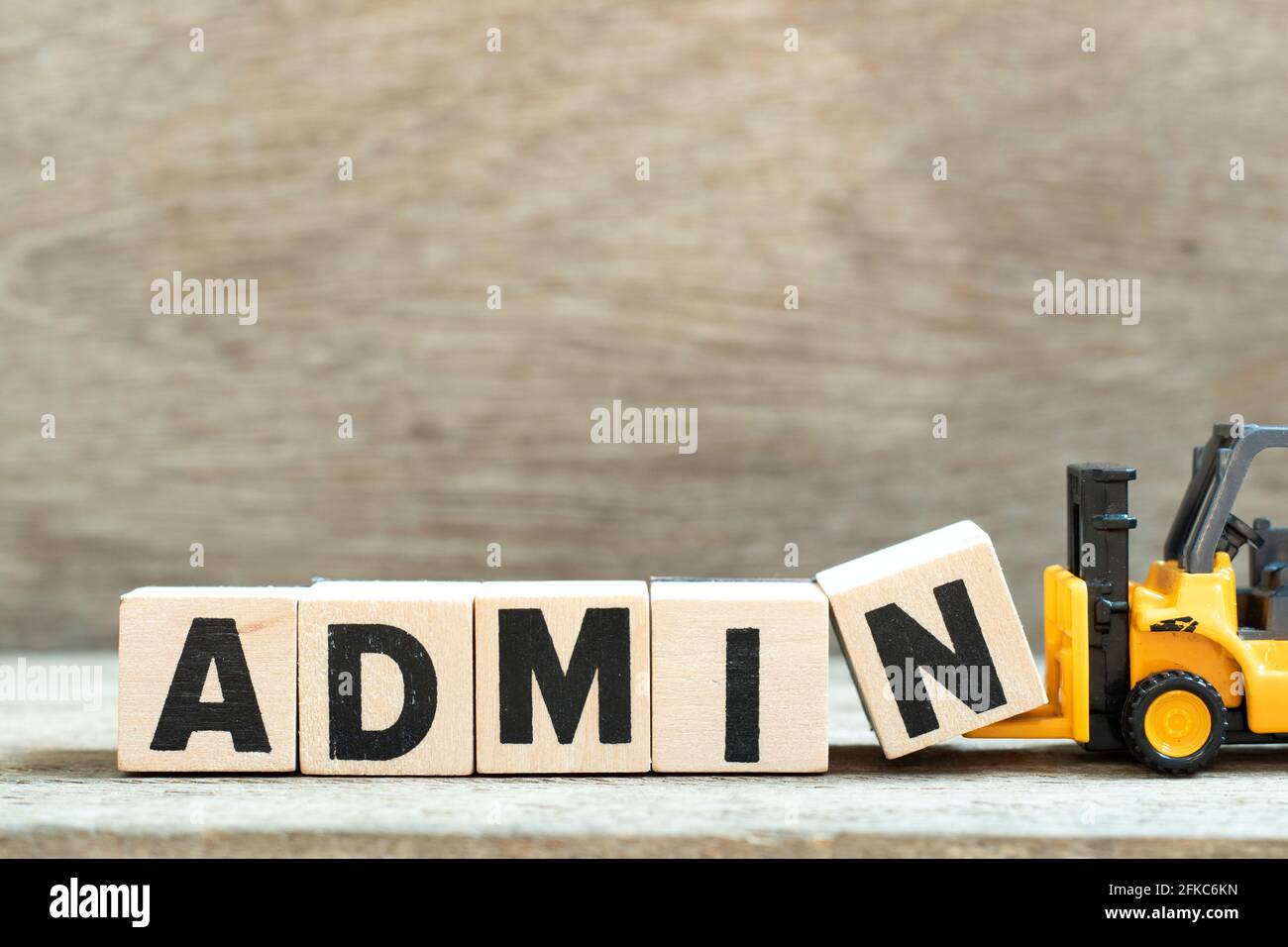 Toy forklift hold letter block n to complete word admin on wood background Stock Photo