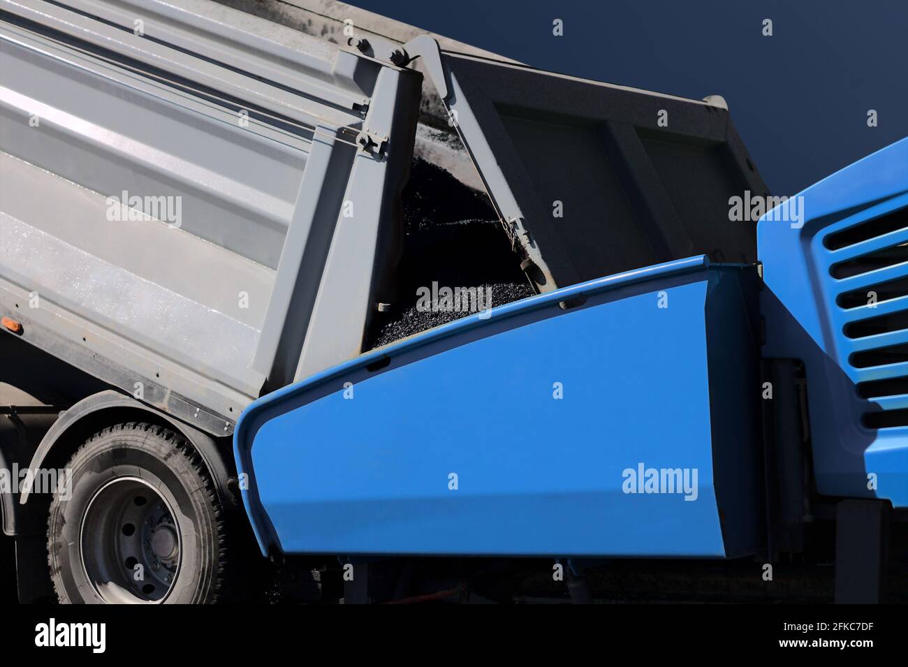 Dump truck with asphalt tar loading asphalting paving paver finisher machine at road construction site Stock Photo