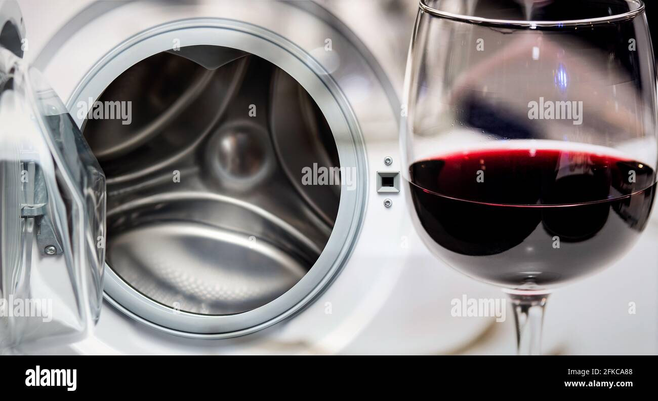 Washing red wine stains. Open washing machine and a glass of red wine