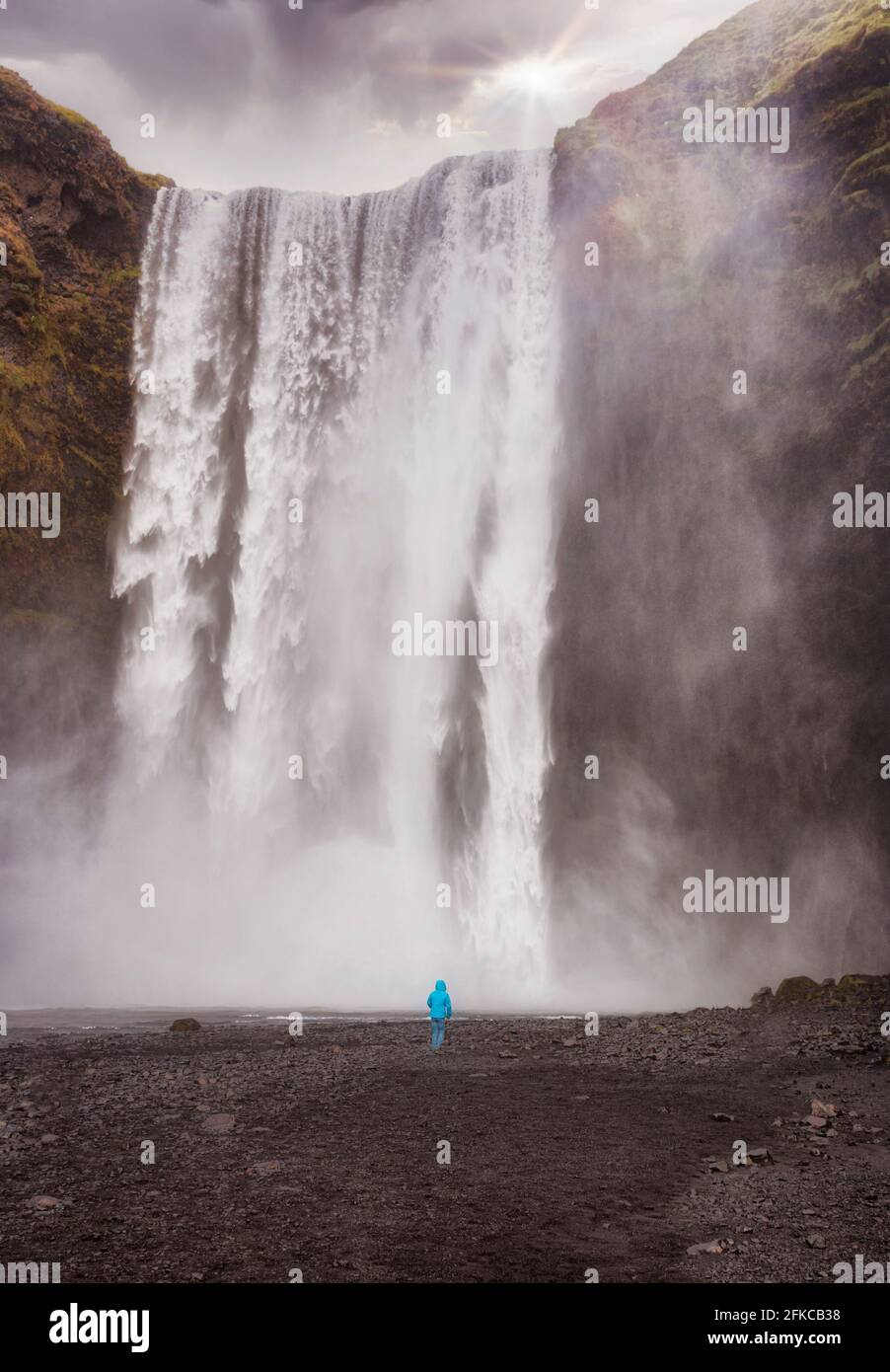 a child stands in front of the waterfall Skogafoss in iceland Stock Photo