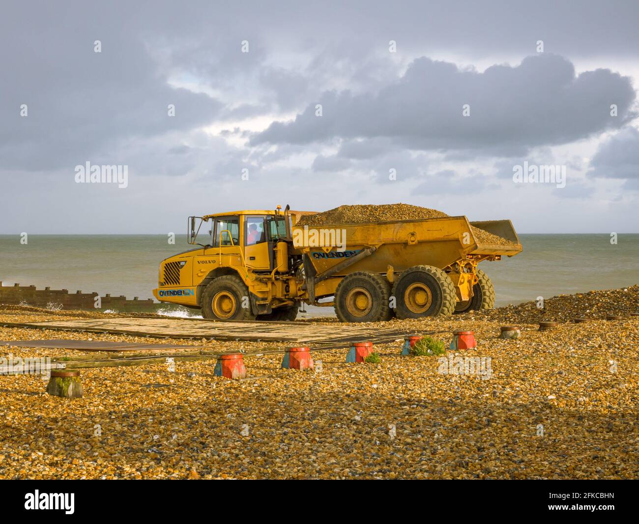 Heavy plant working on Eastbourne beach in East Sussex, UK. Moving shingle from a dreged area of the beach. Stock Photo