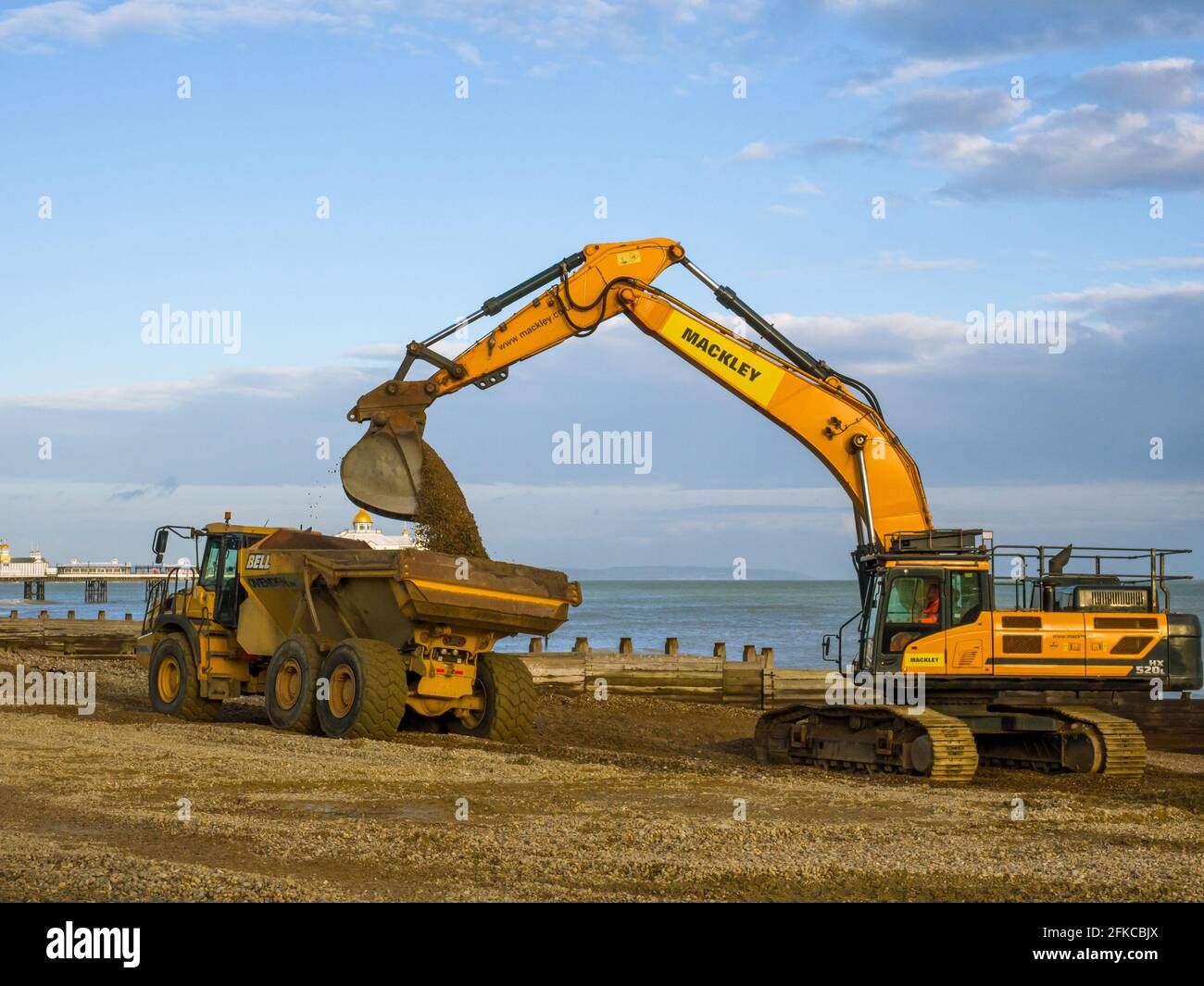 Heavy plant working on Eastbourne beach in East Sussex, UK. Moving shingle from a dreged area of the beach. Stock Photo