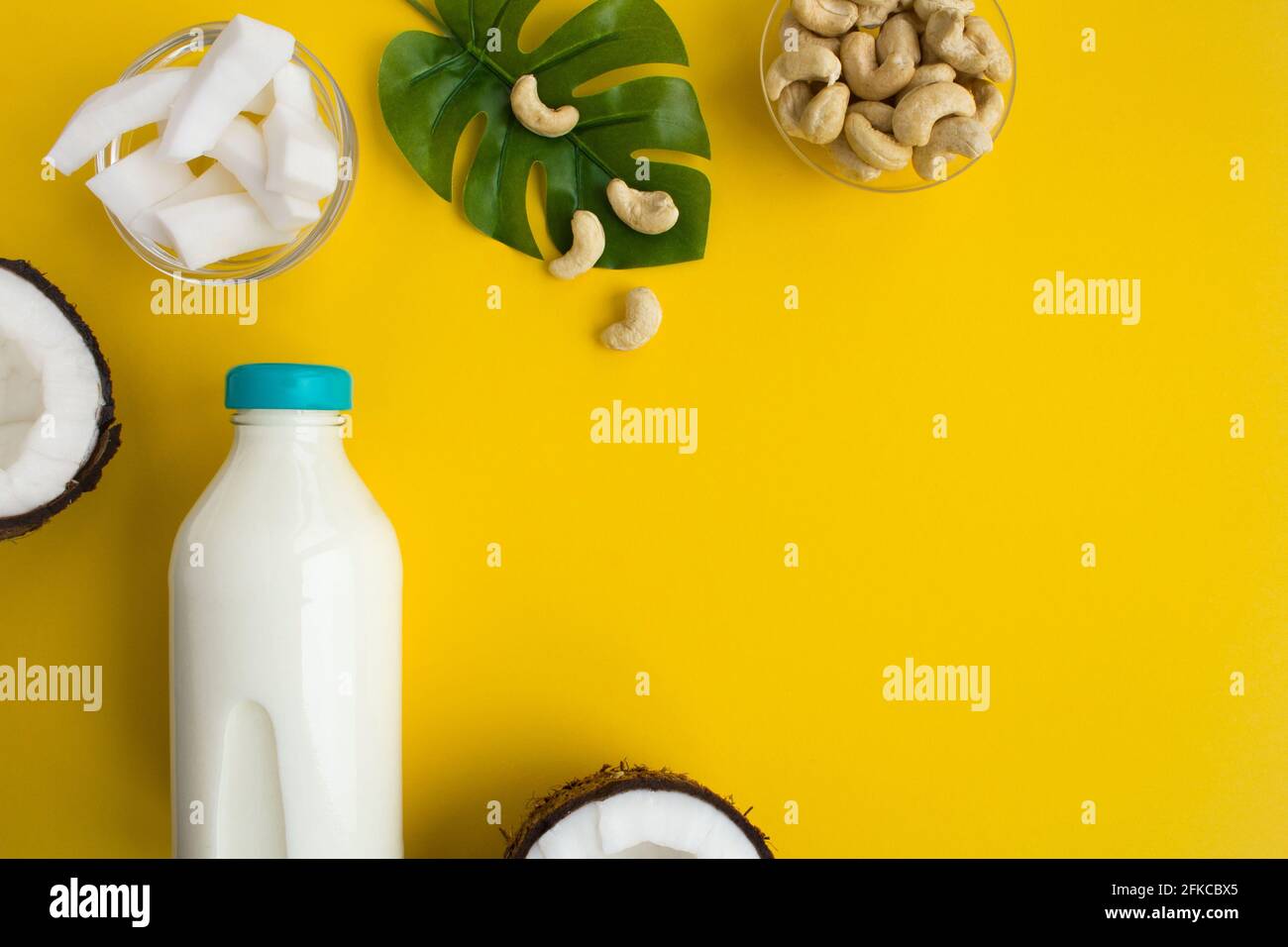 Coconut milk in the glass bottle and cashew nuts on the yellow